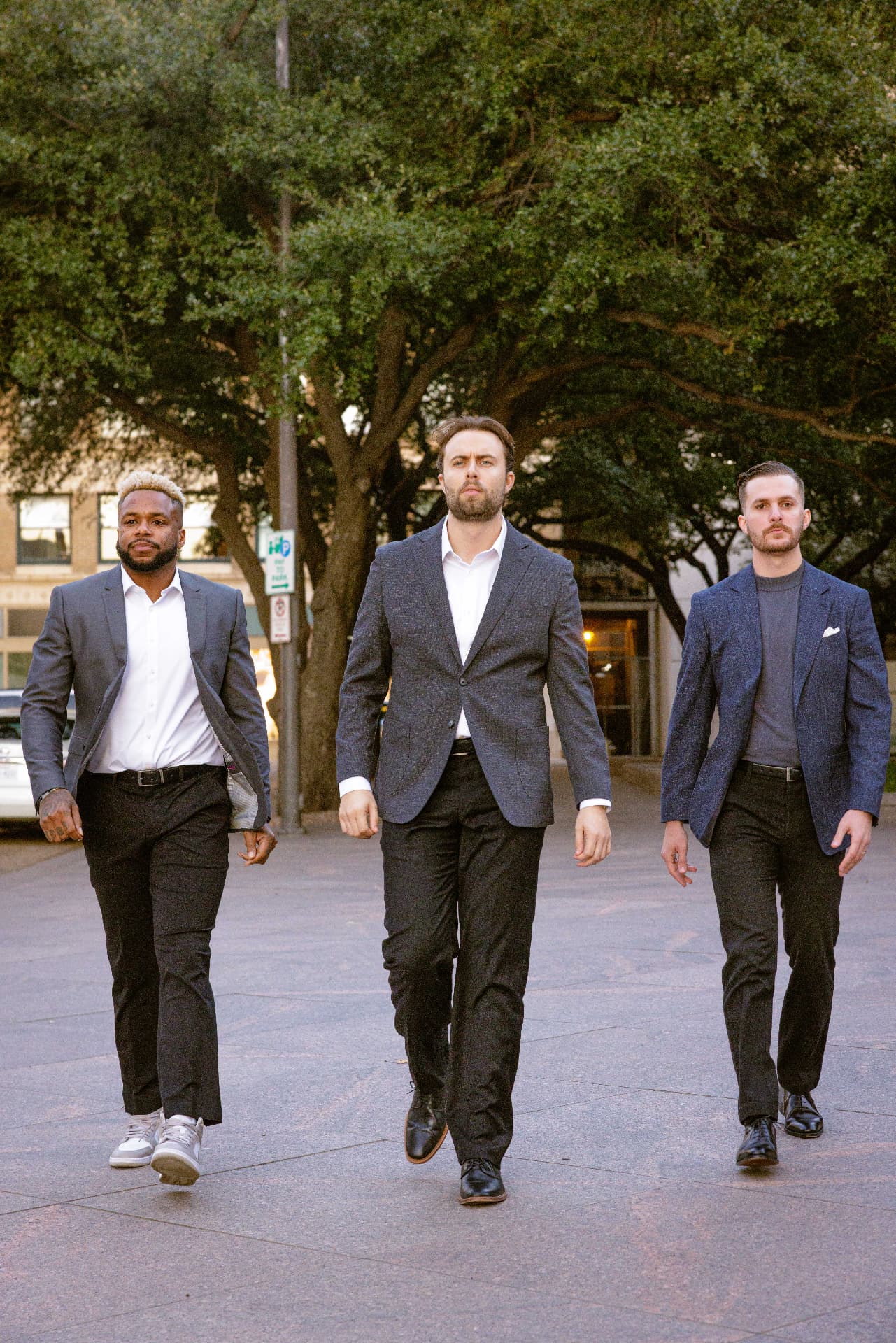 Three TrueGuard property managers in blazers walking side by side across a paved courtyard