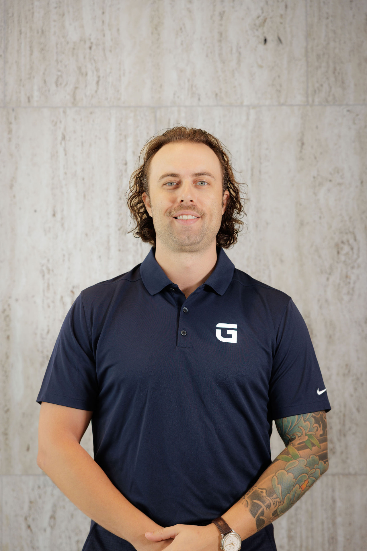 Tom Lail in a navy TrueGuard polo against a travertine stone wall