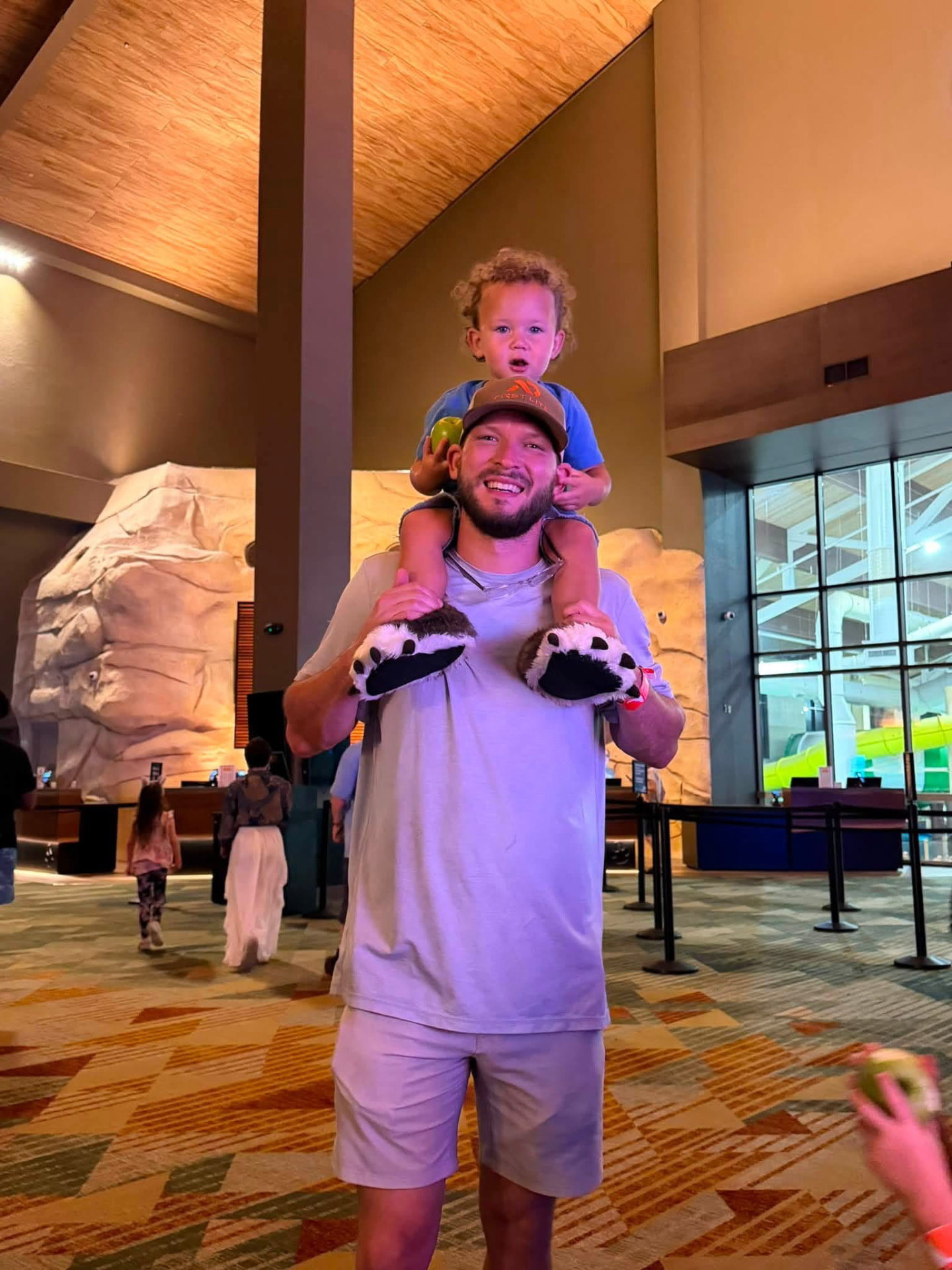 Cody carrying a child on his shoulders indoors