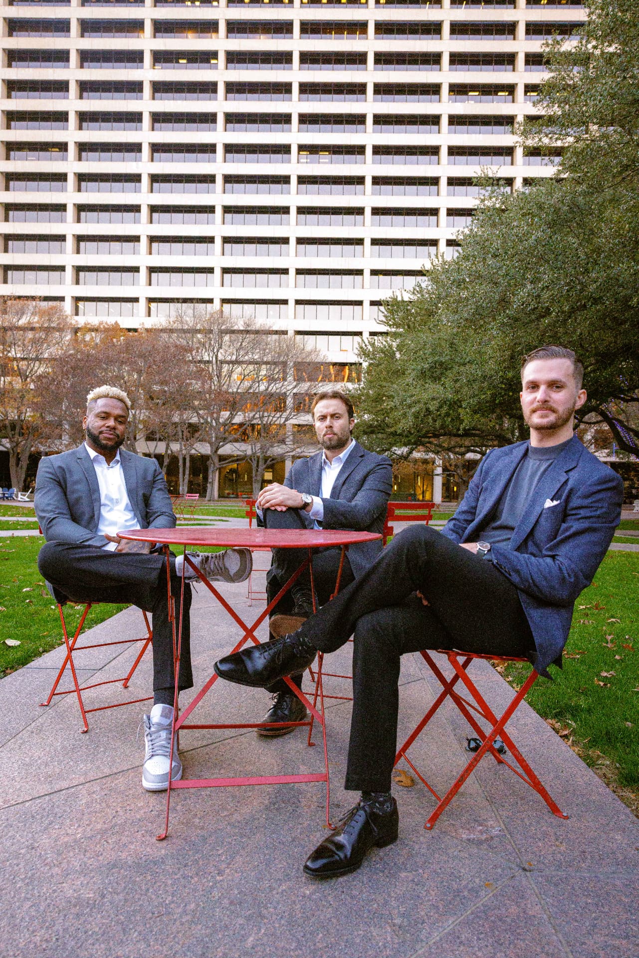 Three TrueGuard property managers seated on red chairs around cafe tables on a lawn