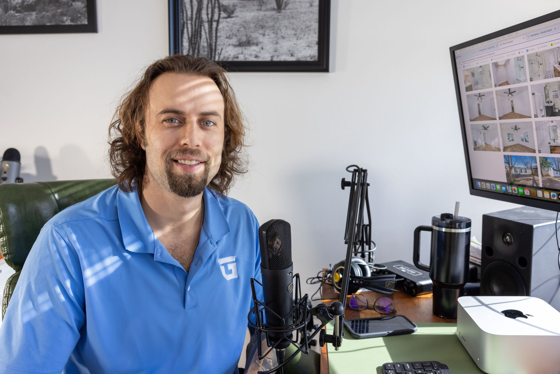 Tom Lail in a blue TrueGuard polo at his desk with a podcast microphone and a monitor of property photos