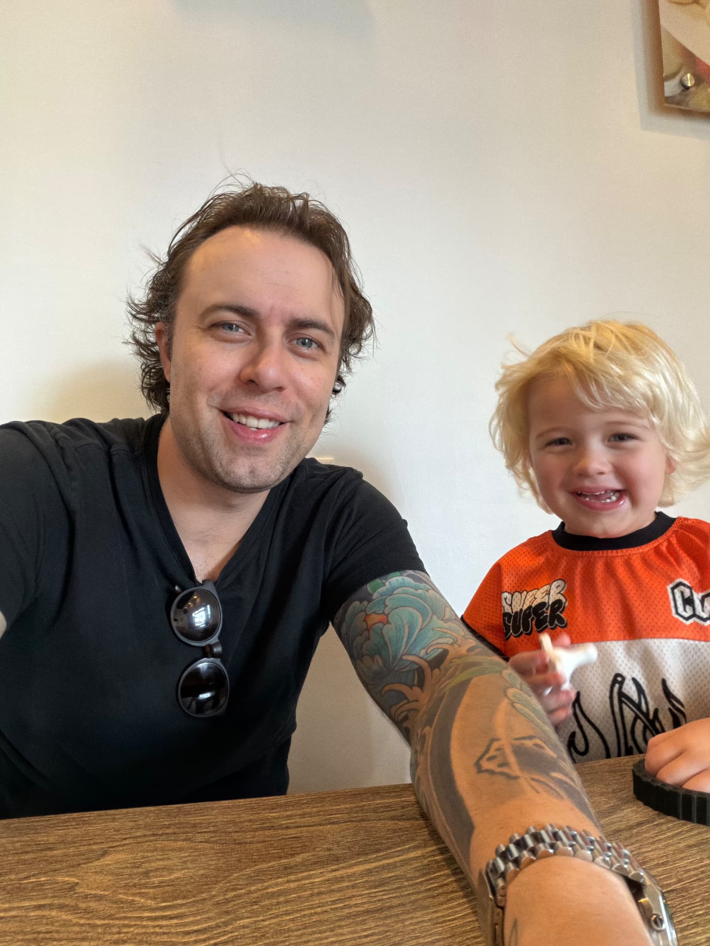 Tom Lail smiling beside a young child seated together at a wooden table
