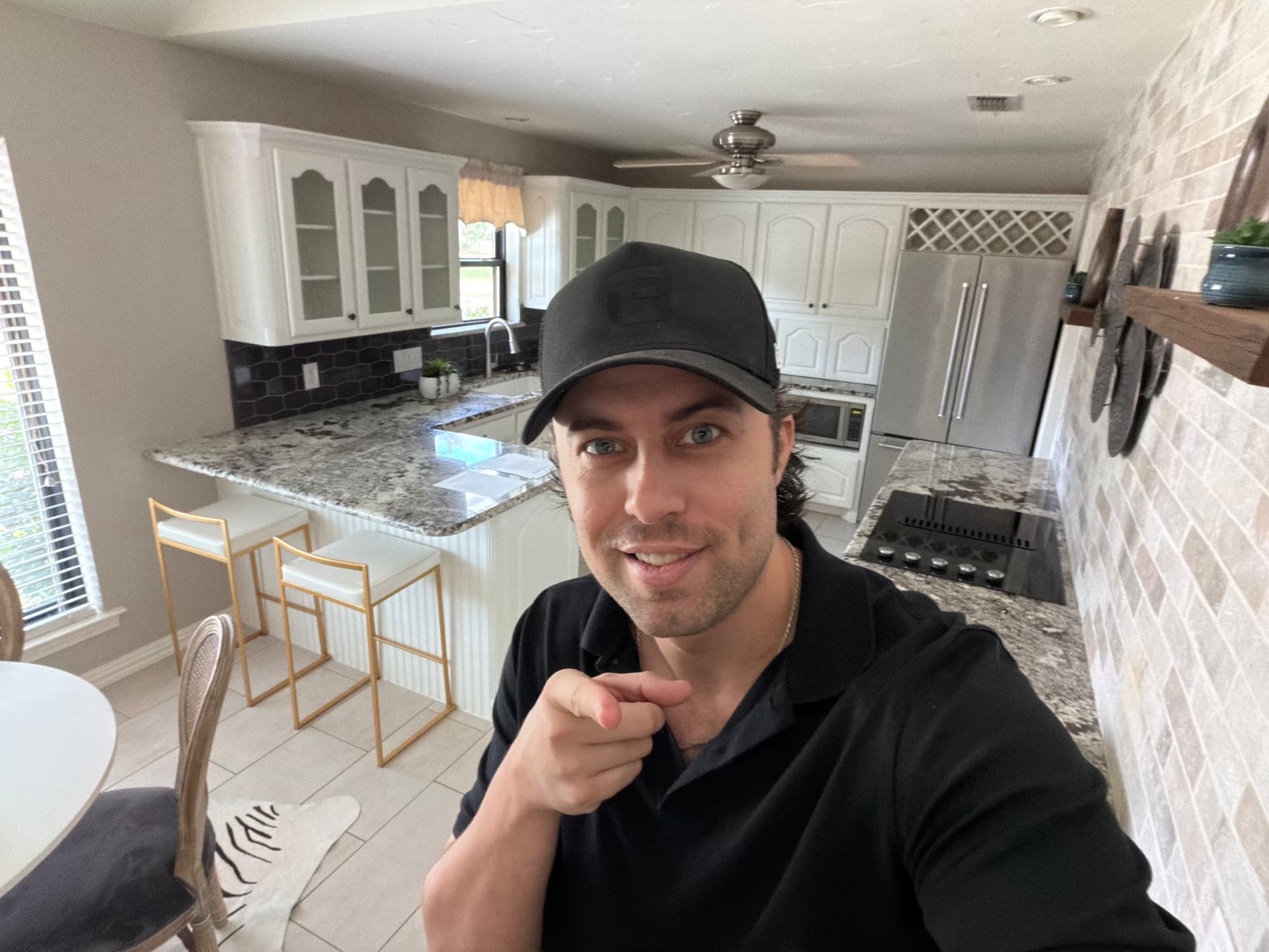 Tom Lail in a black cap and polo inside a freshly renovated kitchen