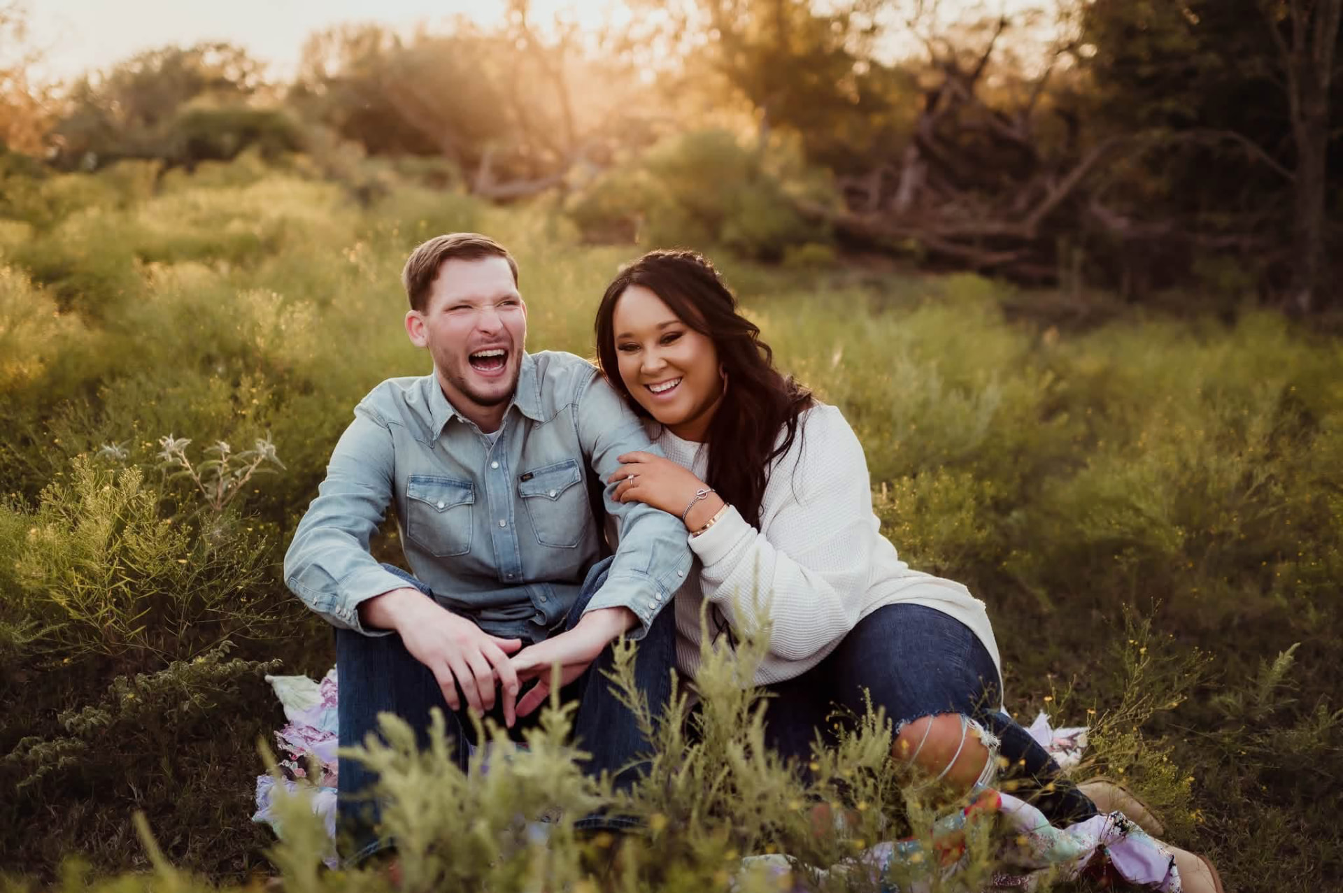 Cody and a woman laughing together in a sunlit meadow